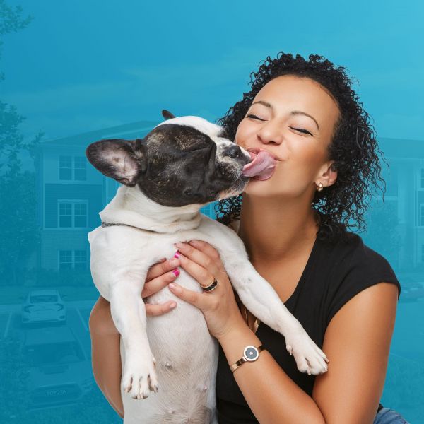 Woman holding dog and smiling while he tries to lick her face