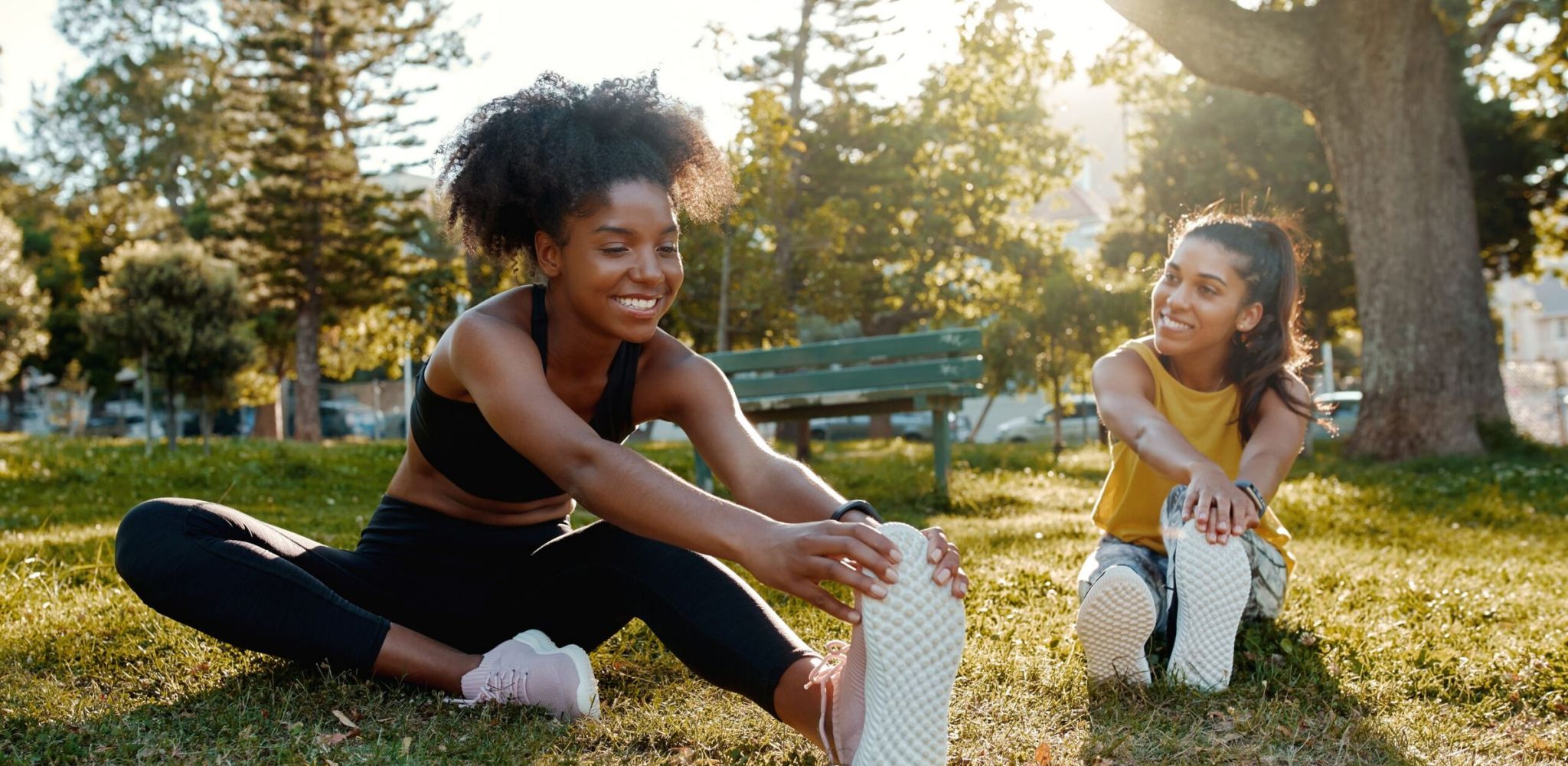 Hawthorne at Holbrook female diverse friends doing stretching exercise in the park - diverse friends warming up before doing group exercise