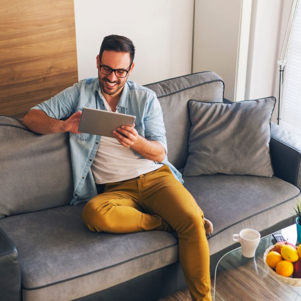 Smiling young man relaxing at home and using tablet